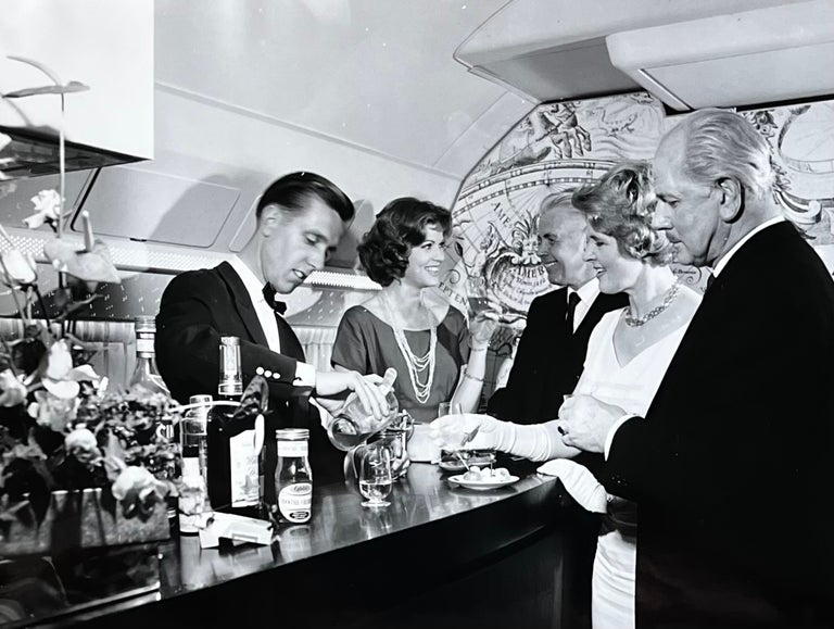Item #227250 1960s Glossy Black and White Photo of Four First Class Passengers Enjoying the First Class Bar on a Lufthansa Flight. Lufthansa Airlines.